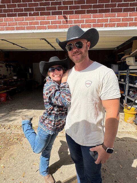 A woman and man in cowboy hats posing together outdoors at Hidden Pastures