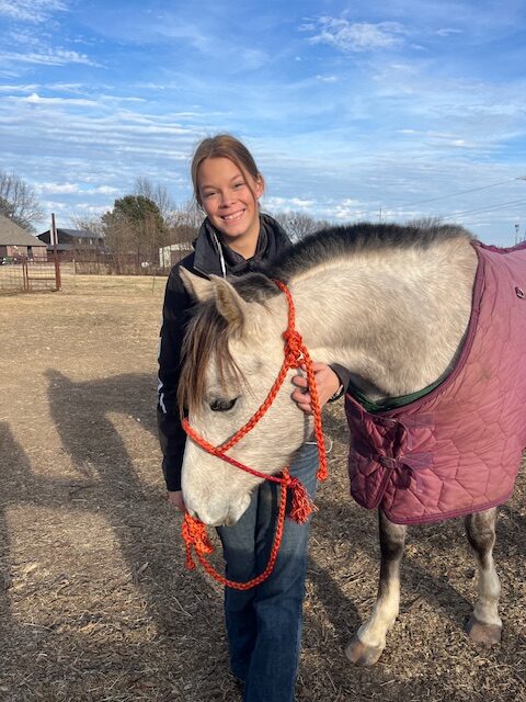 Katie McCutcheon standing beside a horse at Hidden Pastures