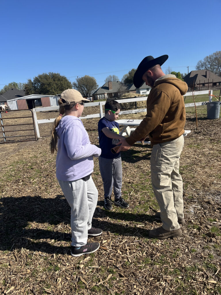 A Hidden Pastures team member guiding two children through the farm