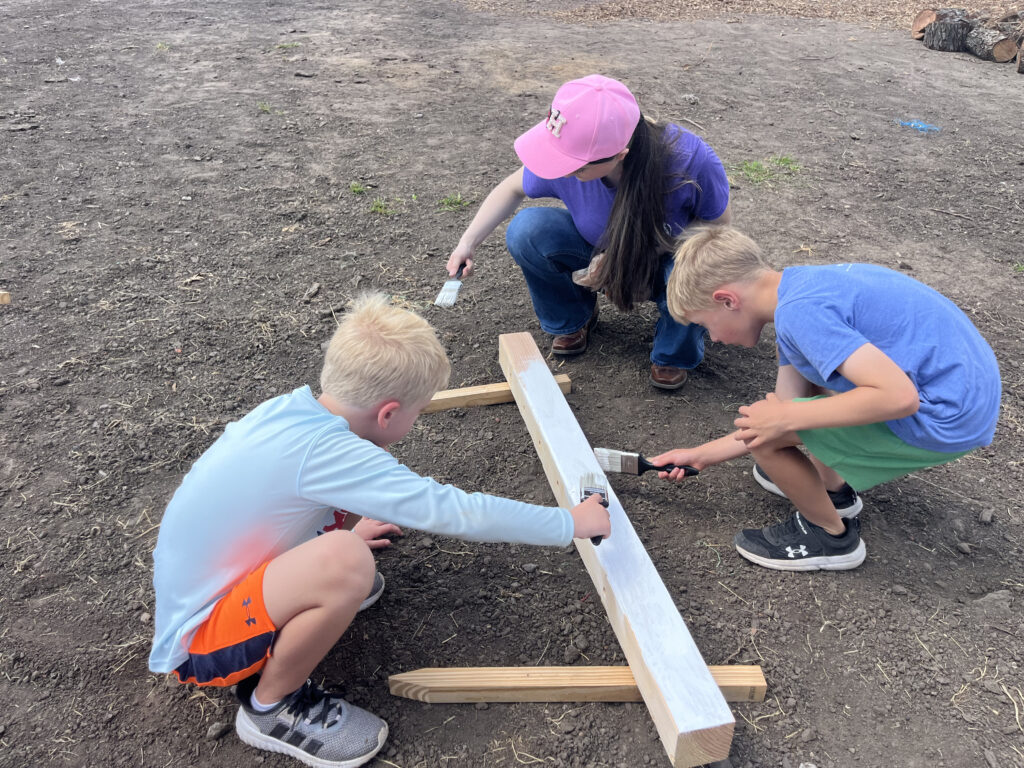 A participant using a tool to build a project at Hidden Pastures
