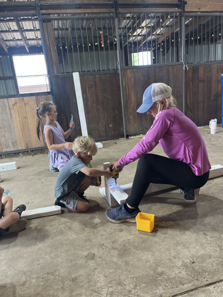 A team member helping children interact with an animal at Hidden Pastures